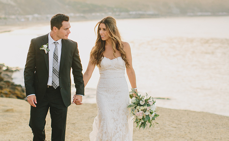 bride and groom walking together on the beach