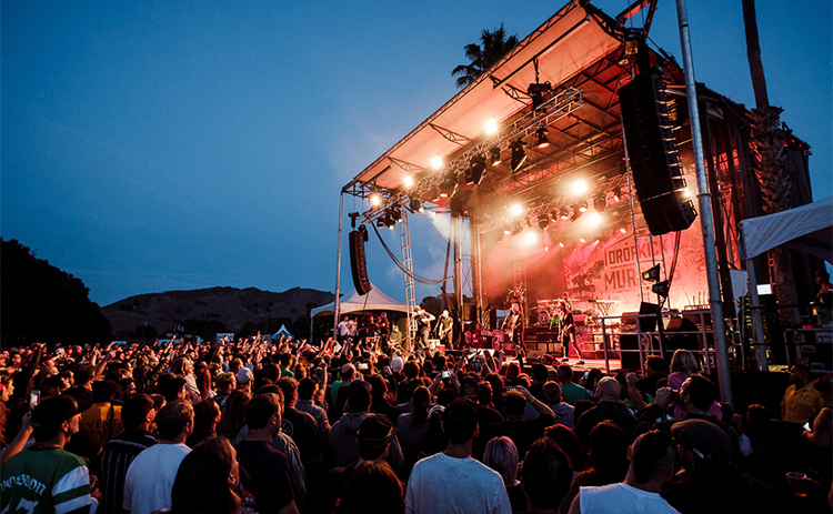 visitor gathered around the stage at a live concert at sunset