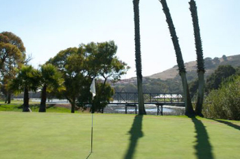 Course greens with a view of  lake and bridge in the background 
